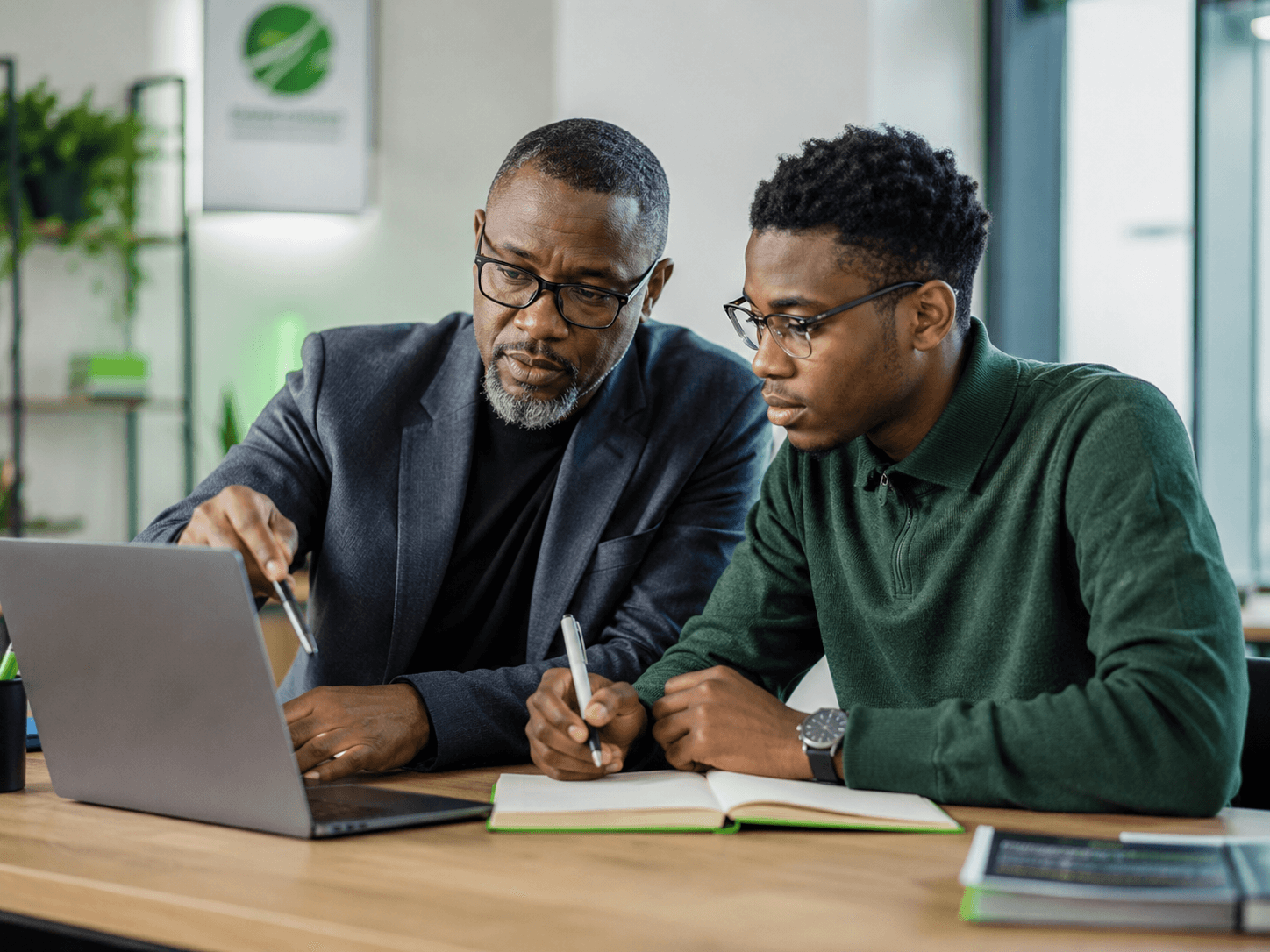 Mentor guiding a young African learner in a modern innovation workspace
